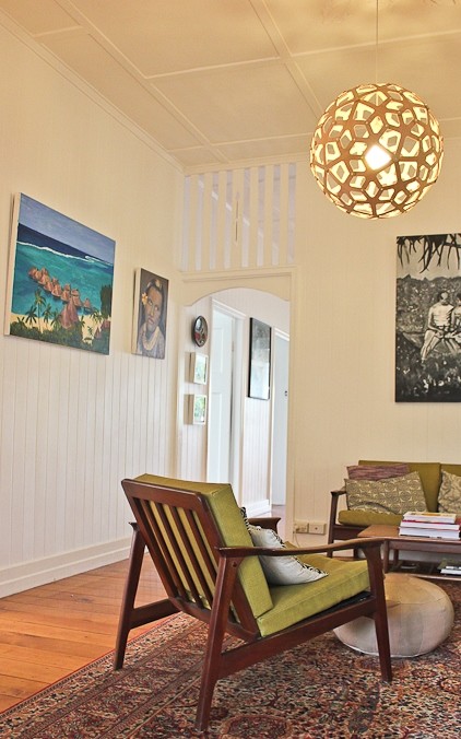Diseño de salón cerrado retro de tamaño medio con paredes blancas, suelo de madera clara y televisor colgado en la pared
