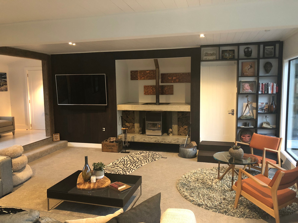 Diseño de salón abierto minimalista de tamaño medio con paredes negras, moqueta, estufa de leña, marco de chimenea de hormigón y televisor colgado en la pared