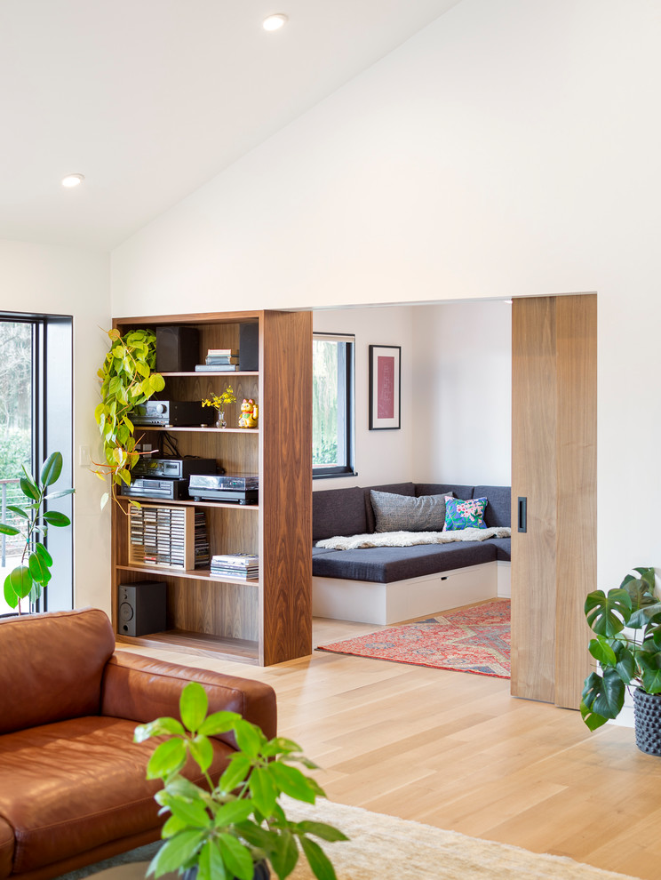 Свежая идея для дизайна: открытая гостиная комната среднего размера в стиле ретро с с книжными шкафами и полками, белыми стенами, светлым паркетным полом, стандартным камином и фасадом камина из дерева - отличное фото интерьера