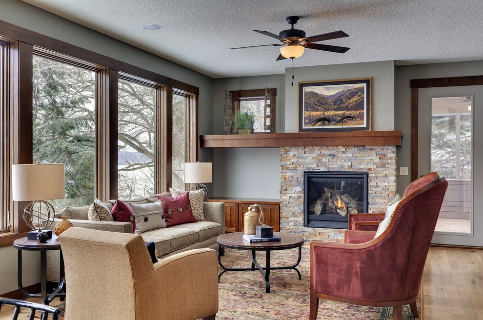 Traditional living room in Minneapolis with grey walls, medium hardwood flooring, a standard fireplace and a stone fireplace surround.