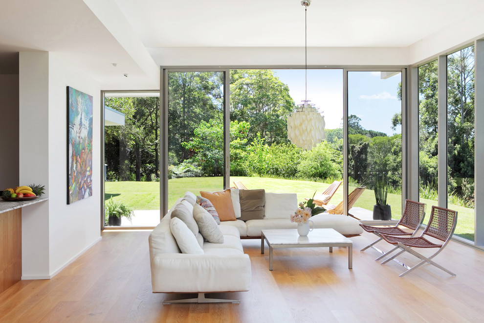 Großes, Offenes Modernes Wohnzimmer mit weißer Wandfarbe, braunem Holzboden und braunem Boden in Sunshine Coast