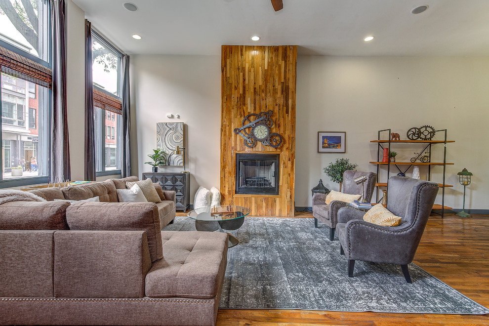 Photo of a medium sized industrial open plan living room in Cincinnati with white walls, medium hardwood flooring, a standard fireplace, a wooden fireplace surround, brown floors and no tv.