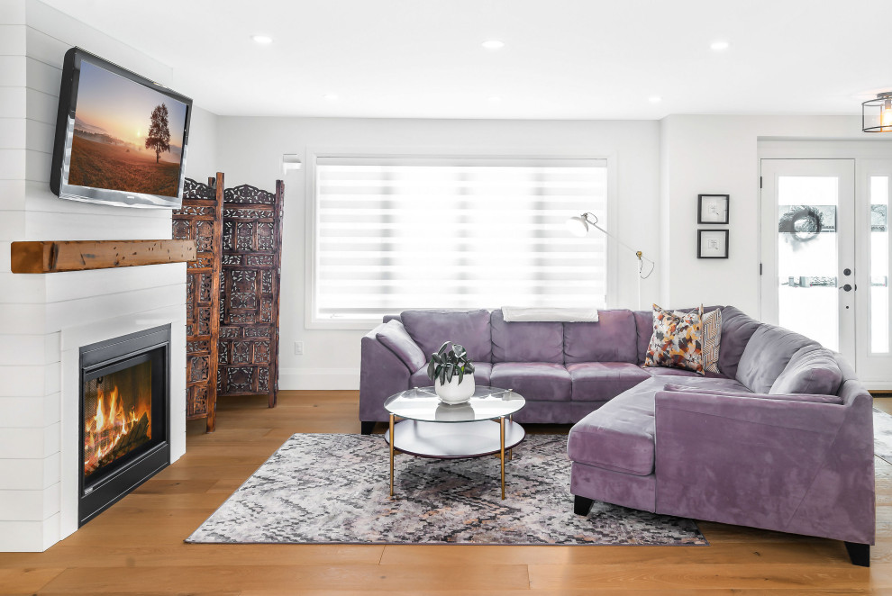 Offenes Klassisches Wohnzimmer mit weißer Wandfarbe, braunem Holzboden, Kamin, TV-Wand und braunem Boden in Toronto