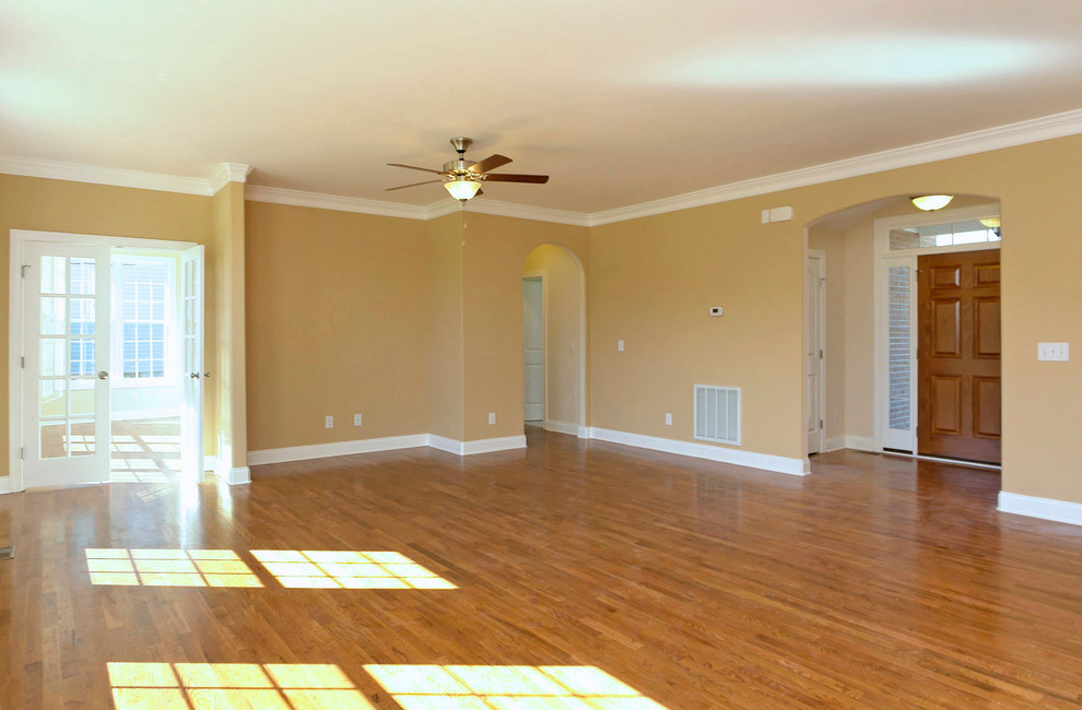 Example of a mid-sized classic enclosed medium tone wood floor living room design in Raleigh with beige walls and a media wall