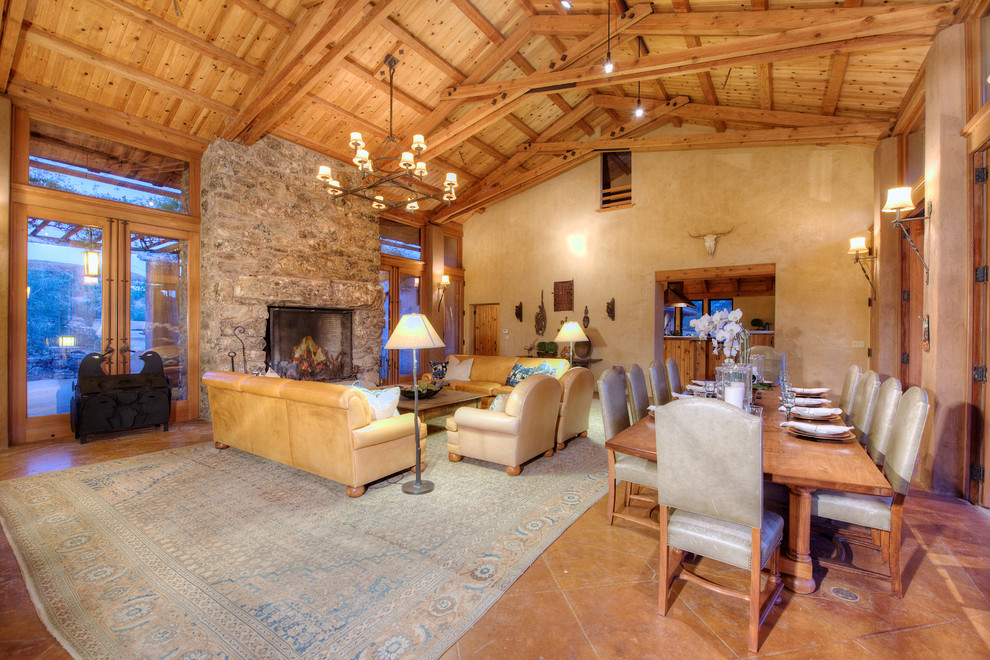 Cette image montre un très grand salon sud-ouest américain ouvert avec une salle de réception, un mur beige, un sol en bois brun, une cheminée standard et un manteau de cheminée en pierre.