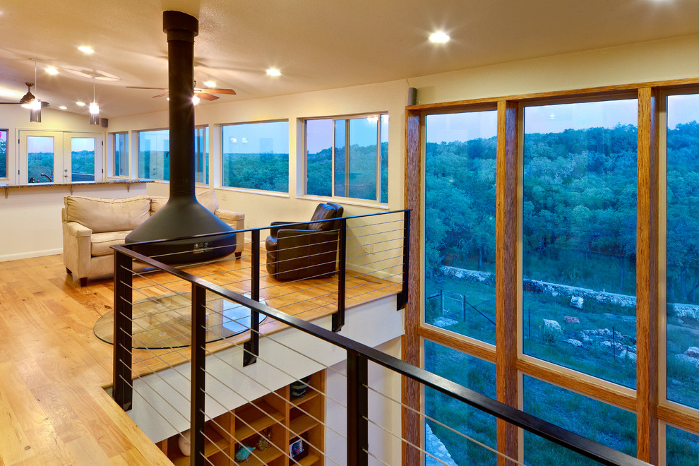 Fernseherloses Modernes Wohnzimmer im Loft-Stil mit Hängekamin, beiger Wandfarbe und braunem Holzboden in Austin