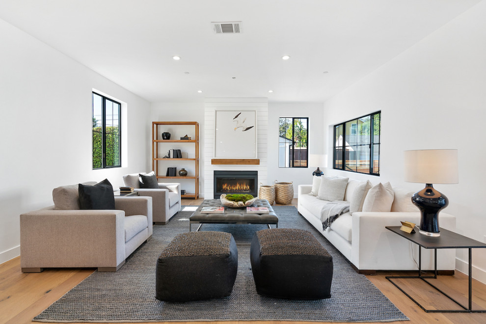 Großes, Repräsentatives Klassisches Wohnzimmer mit weißer Wandfarbe, braunem Holzboden, Kamin, Kaminumrandung aus Metall und braunem Boden in Los Angeles