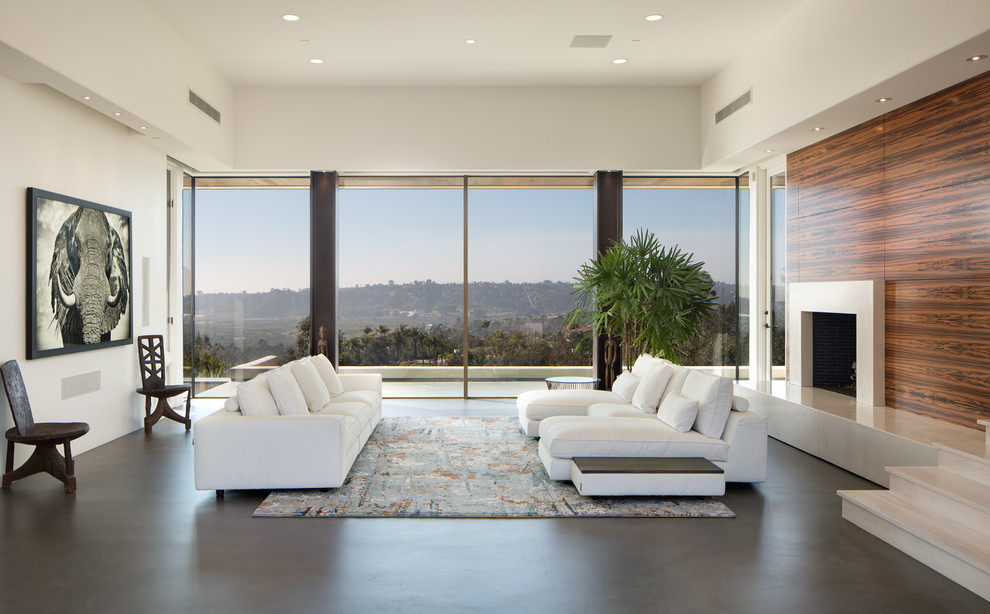 Großes, Repräsentatives, Offenes Modernes Wohnzimmer mit weißer Wandfarbe, Betonboden, Kamin, Kaminumrandung aus Holz, verstecktem TV und grauem Boden in San Diego