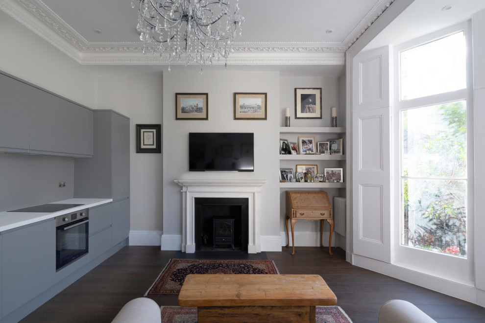 Mittelgroßes, Offenes Klassisches Wohnzimmer mit grauer Wandfarbe, Kamin, Kaminumrandung aus Holz und grauem Boden in London