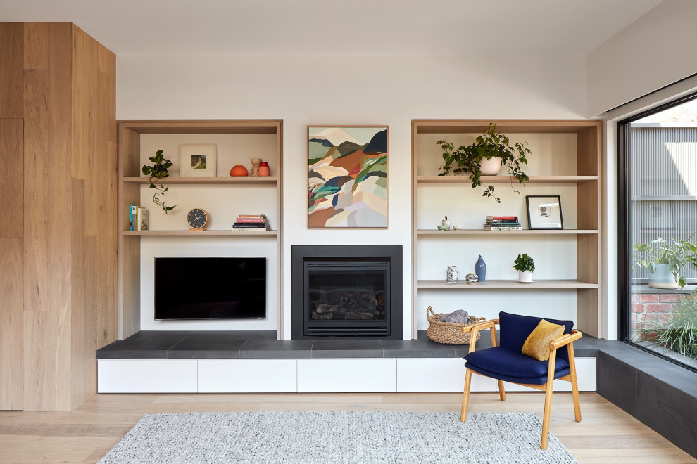 This is an example of a medium sized contemporary open plan living room in Melbourne with white walls, medium hardwood flooring, a standard fireplace, a metal fireplace surround, a wall mounted tv and beige floors.