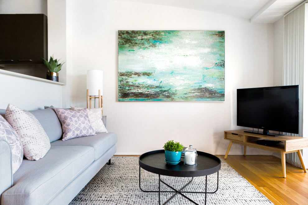 Foto på ett litet minimalistiskt loftrum, med beige väggar, ljust trägolv och en fristående TV
