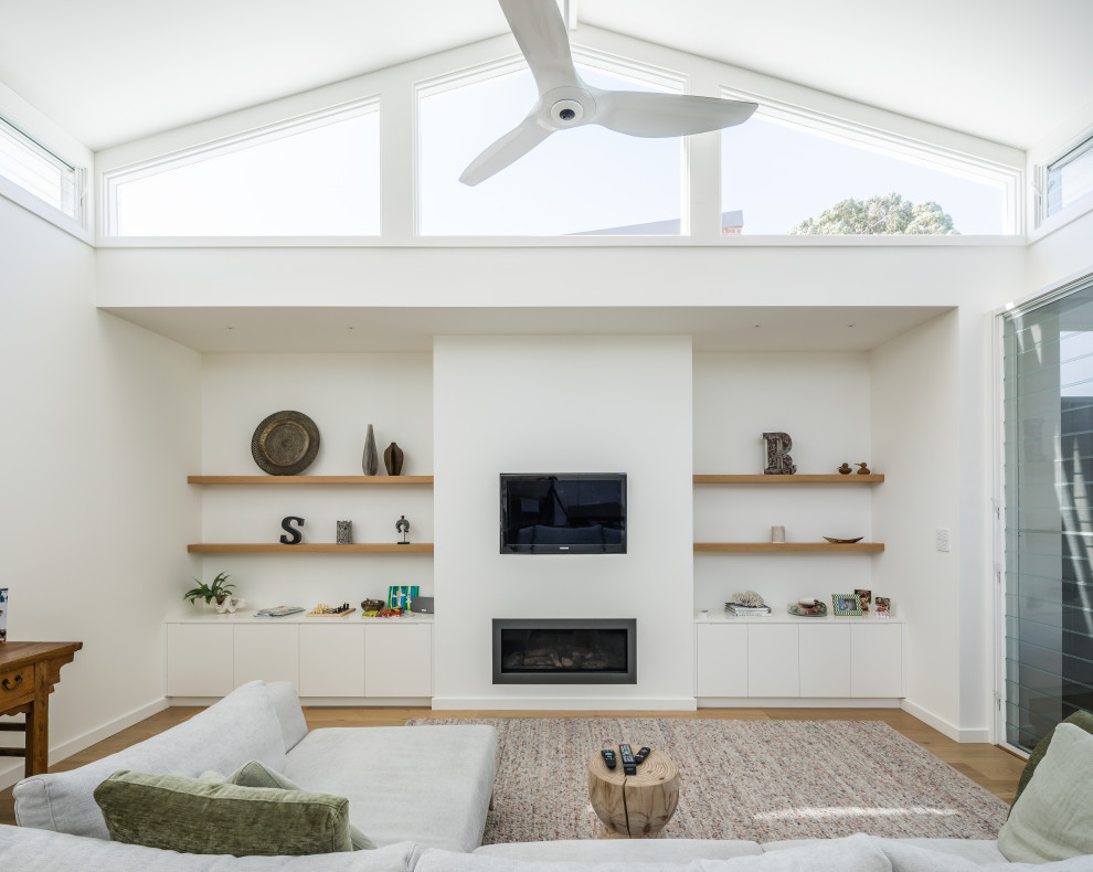 Immagine di un soggiorno design aperto con parquet chiaro, TV a parete e pavimento marrone