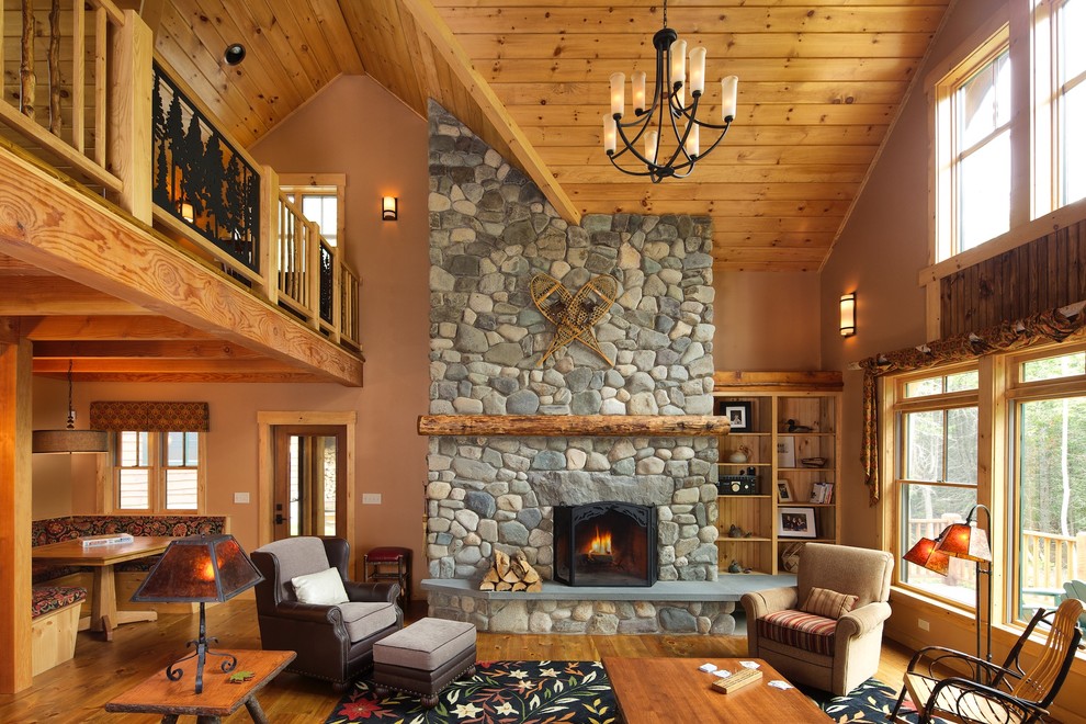 This is an example of a rustic living room in Portland Maine with beige walls, medium hardwood flooring, a standard fireplace and a stone fireplace surround.