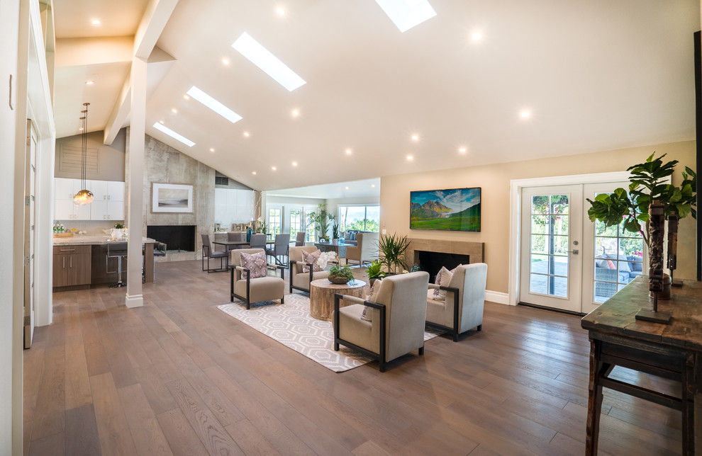 Inspiration for a large transitional formal and open concept medium tone wood floor and brown floor living room remodel in Los Angeles with multicolored walls, a standard fireplace, a stone fireplace and a wall-mounted tv