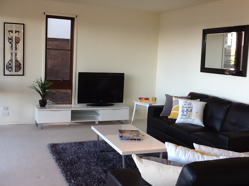 Offenes Modernes Wohnzimmer ohne Kamin mit weißer Wandfarbe, Teppichboden und freistehendem TV in Newcastle - Maitland