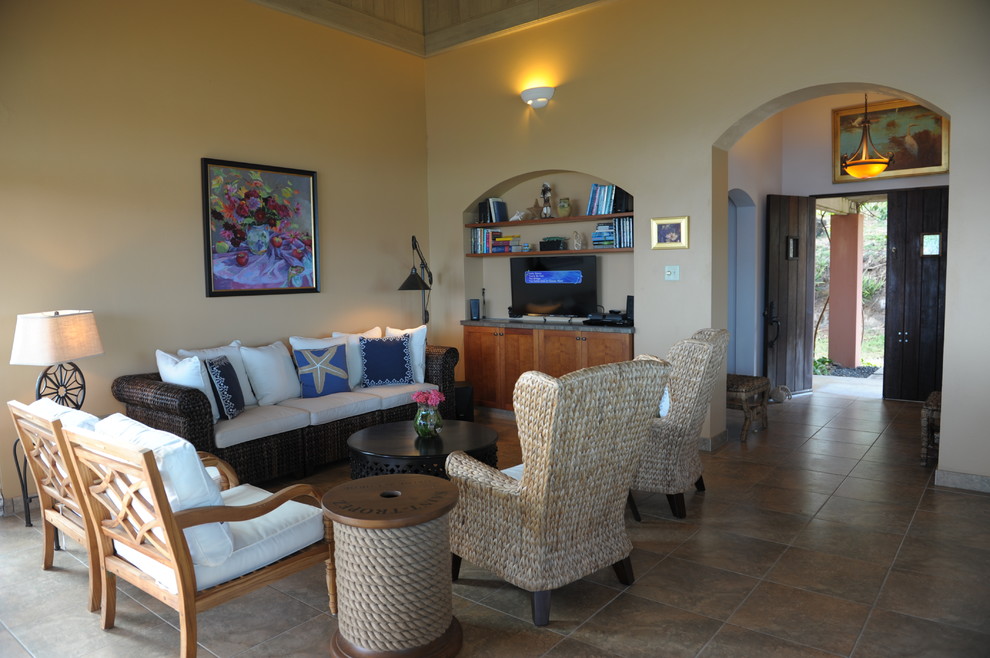Foto di un grande soggiorno tropicale aperto con pareti arancioni, pavimento in gres porcellanato e TV a parete