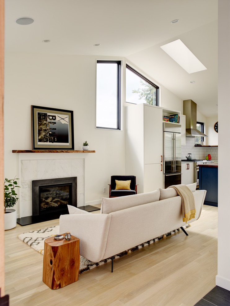Идея дизайна: открытая гостиная комната в современном стиле с белыми стенами, светлым паркетным полом, стандартным камином, фасадом камина из плитки, телевизором на стене и бежевым полом