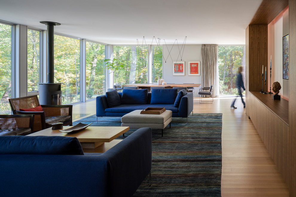 Immagine di un soggiorno minimal aperto con pareti grigie, pavimento in legno massello medio, stufa a legna e pavimento marrone