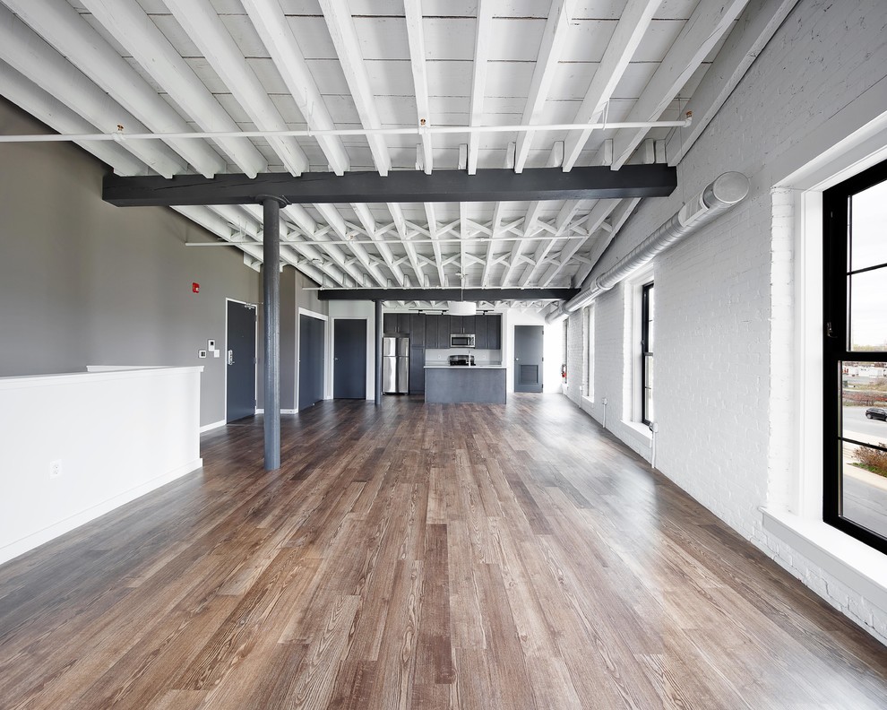 Foto de salón abierto industrial grande sin chimenea con paredes blancas, suelo de madera en tonos medios y suelo marrón