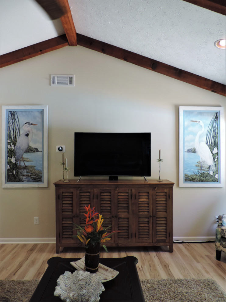 Maritim inredning av ett stort allrum med öppen planlösning, med beige väggar, laminatgolv, en standard öppen spis, en spiselkrans i trä, en fristående TV och flerfärgat golv