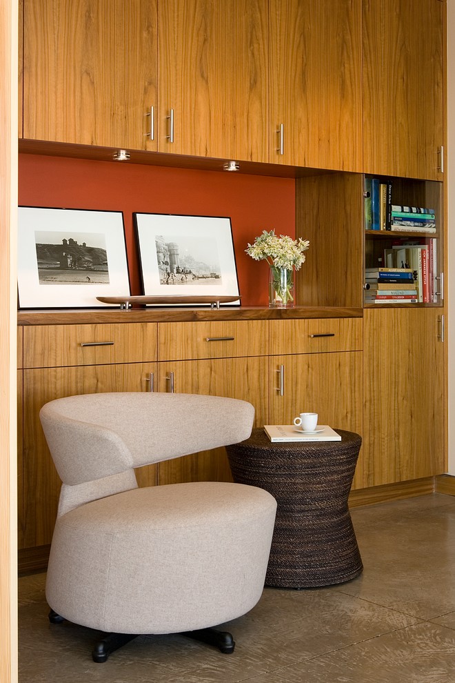 Cette image montre un petit salon design avec sol en béton ciré et une bibliothèque ou un coin lecture.