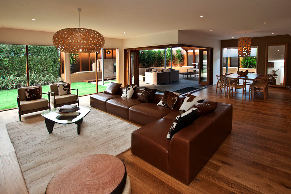 Пример оригинального дизайна: большая парадная, открытая гостиная комната в стиле модернизм с коричневыми стенами и паркетным полом среднего тона