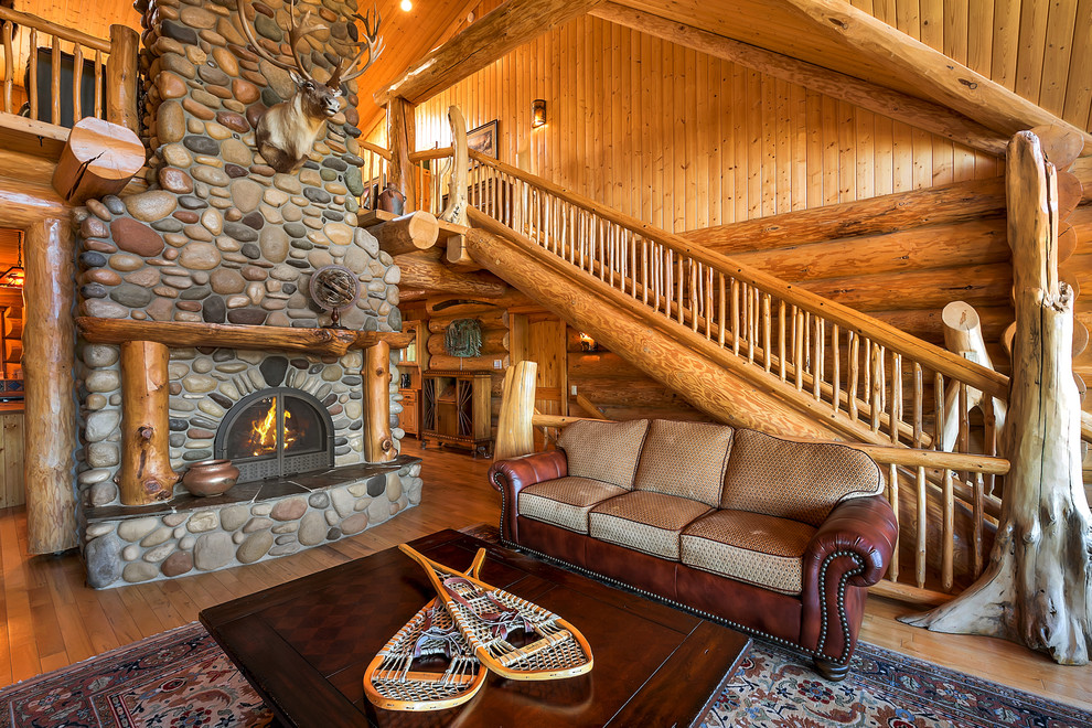 Idée de décoration pour un salon chalet avec un sol en bois brun, une cheminée standard, un manteau de cheminée en pierre et un sol orange.