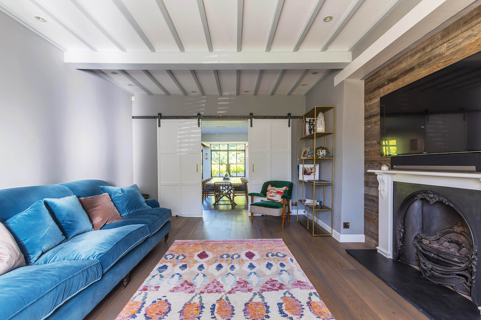 На фото: изолированная гостиная комната среднего размера в современном стиле с серыми стенами, паркетным полом среднего тона, стандартным камином, фасадом камина из металла и коричневым полом с