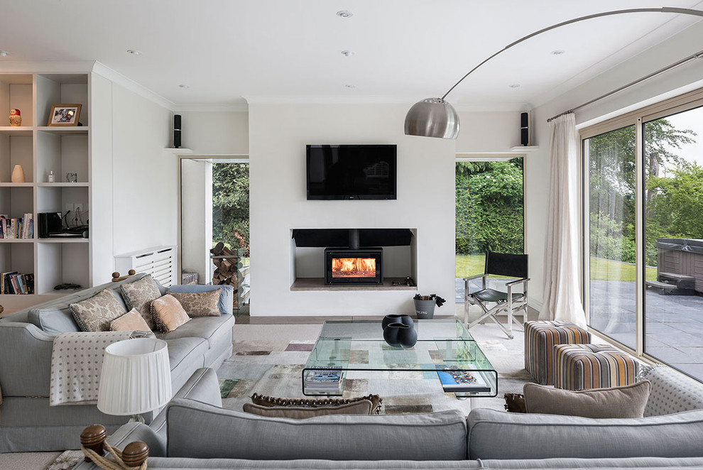 Immagine di un soggiorno contemporaneo con stufa a legna, TV a parete, pareti bianche e moquette