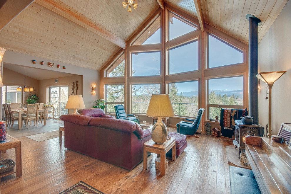 Esempio di un grande soggiorno stile americano aperto con pareti beige, pavimento in legno massello medio e stufa a legna