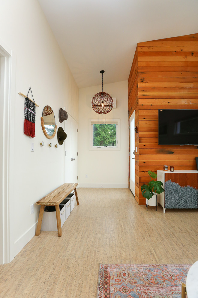 На фото: маленькая открытая гостиная комната в скандинавском стиле с белыми стенами, пробковым полом и телевизором на стене для на участке и в саду с