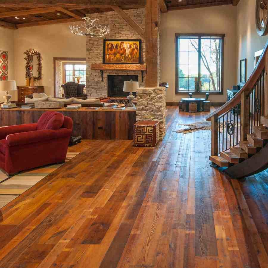 Example of a large mountain style formal and open concept medium tone wood floor living room design in Los Angeles with beige walls, a wood stove, a stone fireplace and a media wall