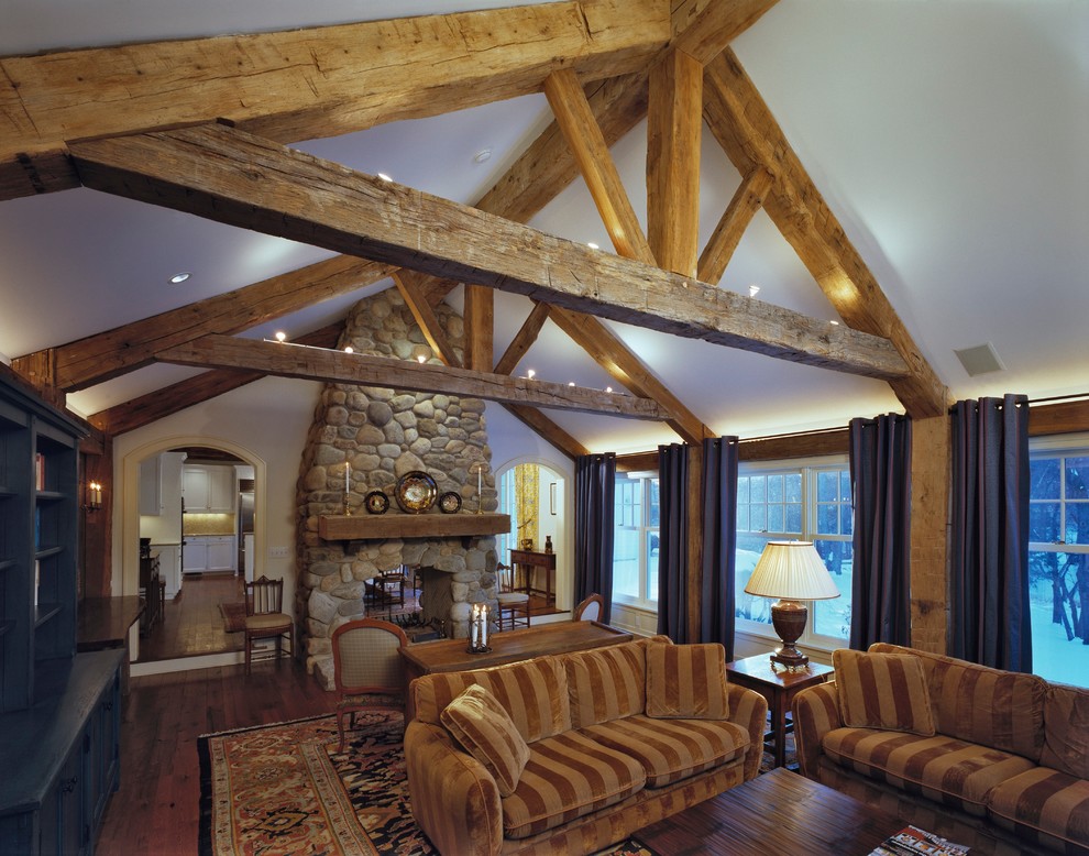 Exemple d'un grand salon montagne avec parquet foncé, une cheminée double-face, un manteau de cheminée en pierre et un sol marron.