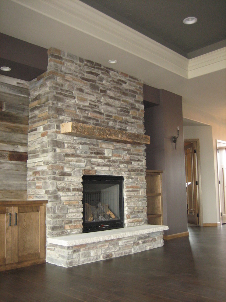 Пример оригинального дизайна: открытая гостиная комната среднего размера в стиле рустика с коричневыми стенами, темным паркетным полом, стандартным камином, фасадом камина из камня и телевизором на стене
