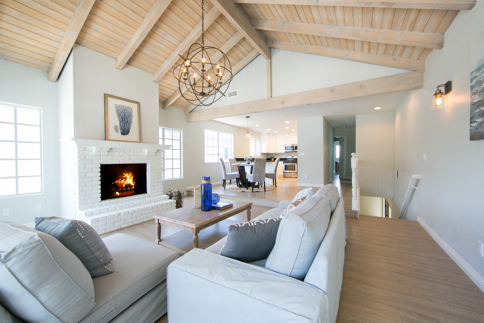 Photo of a beach style living room in Los Angeles with grey walls, medium hardwood flooring, a standard fireplace and a brick fireplace surround.