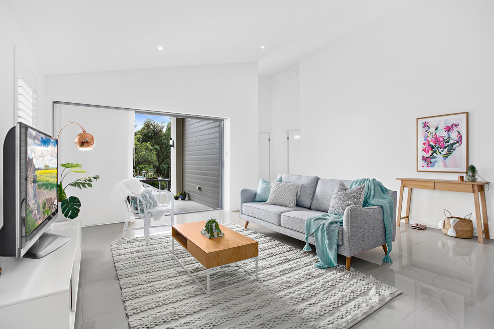 Maritimes Wohnzimmer mit weißer Wandfarbe, freistehendem TV und grauem Boden in Sonstige