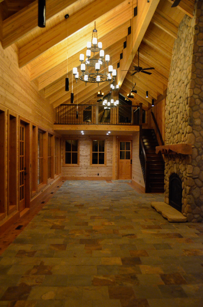 Großes, Offenes Uriges Wohnzimmer mit Schieferboden, Kamin, Kaminumrandung aus Stein und buntem Boden in Calgary