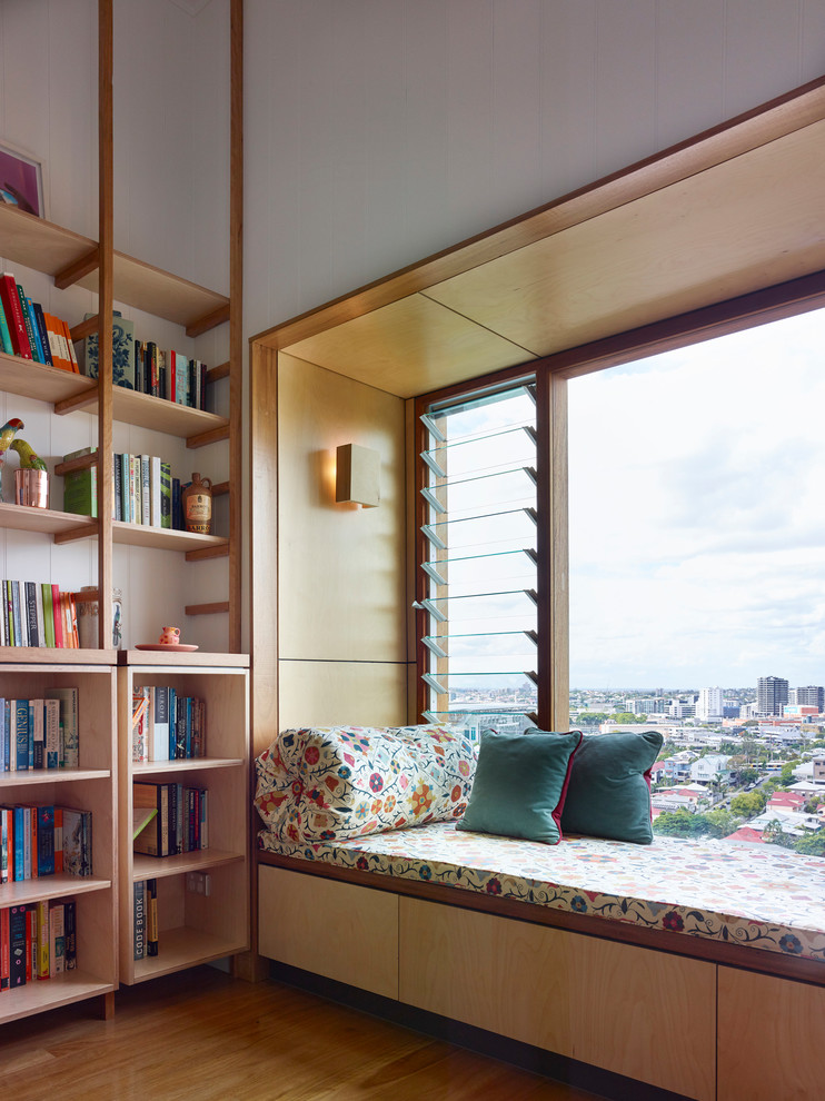 Cette image montre un petit salon design fermé avec une bibliothèque ou un coin lecture, un mur blanc, parquet clair et aucun téléviseur.