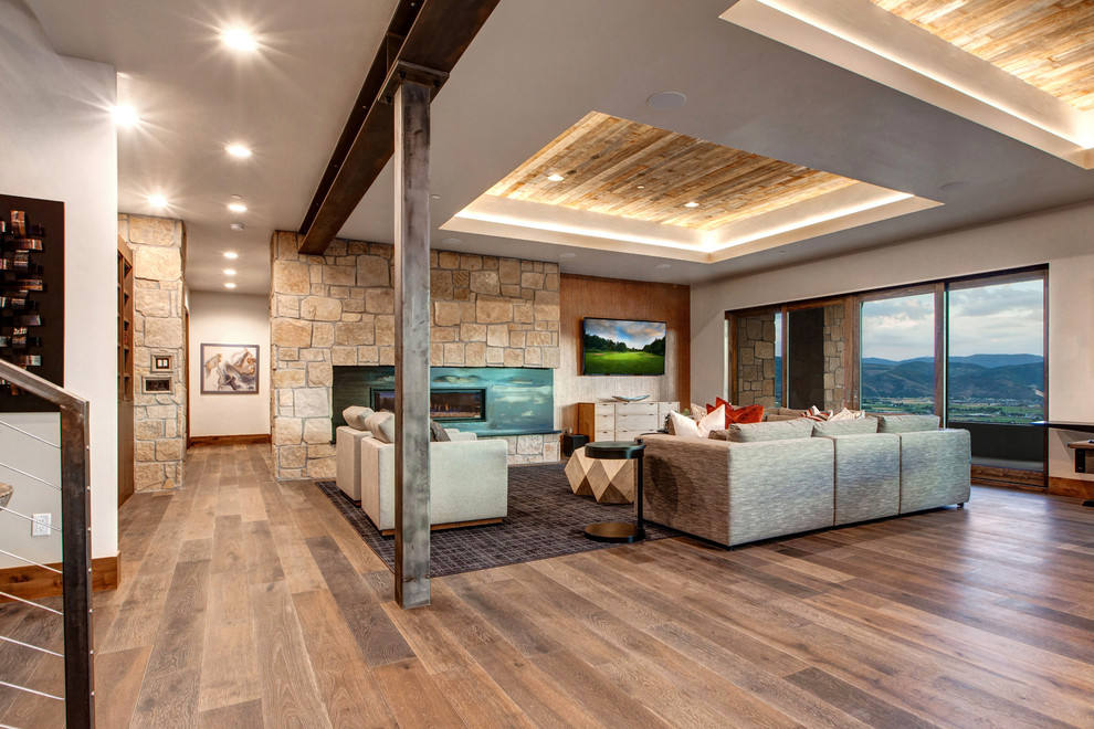 Offenes Klassisches Wohnzimmer mit weißer Wandfarbe, braunem Holzboden, Gaskamin, Kaminumrandung aus Stein, TV-Wand und braunem Boden in Salt Lake City