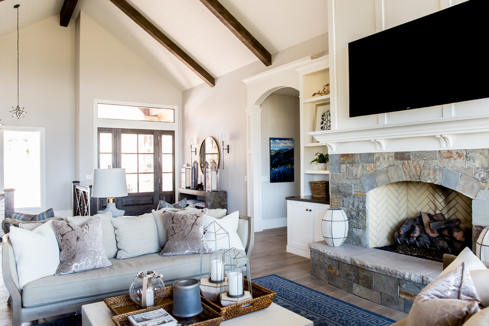 Inspiration for a large rural open plan living room in Salt Lake City with white walls, medium hardwood flooring, a standard fireplace, a stone fireplace surround, a wall mounted tv and feature lighting.