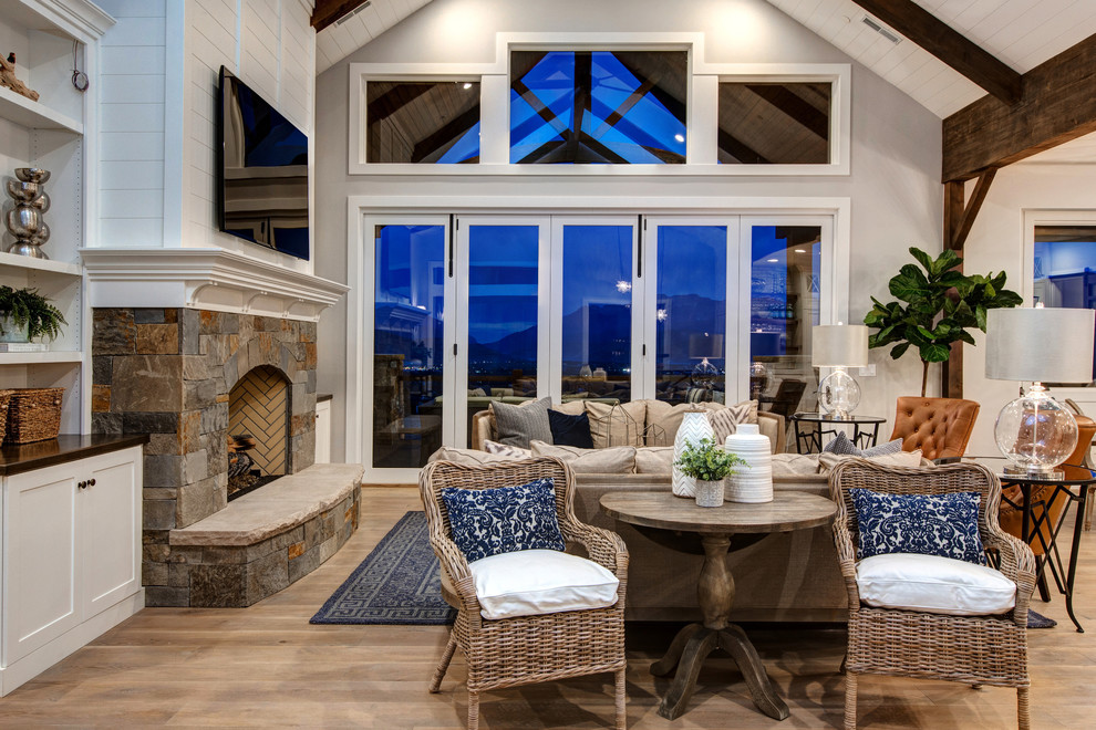 Example of a large farmhouse open concept medium tone wood floor living room design in Salt Lake City with white walls, a standard fireplace, a stone fireplace and a wall-mounted tv