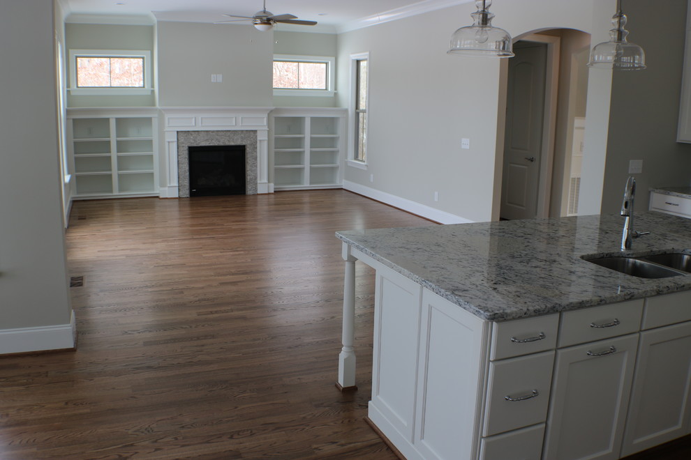 Großes, Offenes Klassisches Wohnzimmer mit grauer Wandfarbe, braunem Holzboden, Kamin, Kaminumrandung aus Stein und braunem Boden in Raleigh