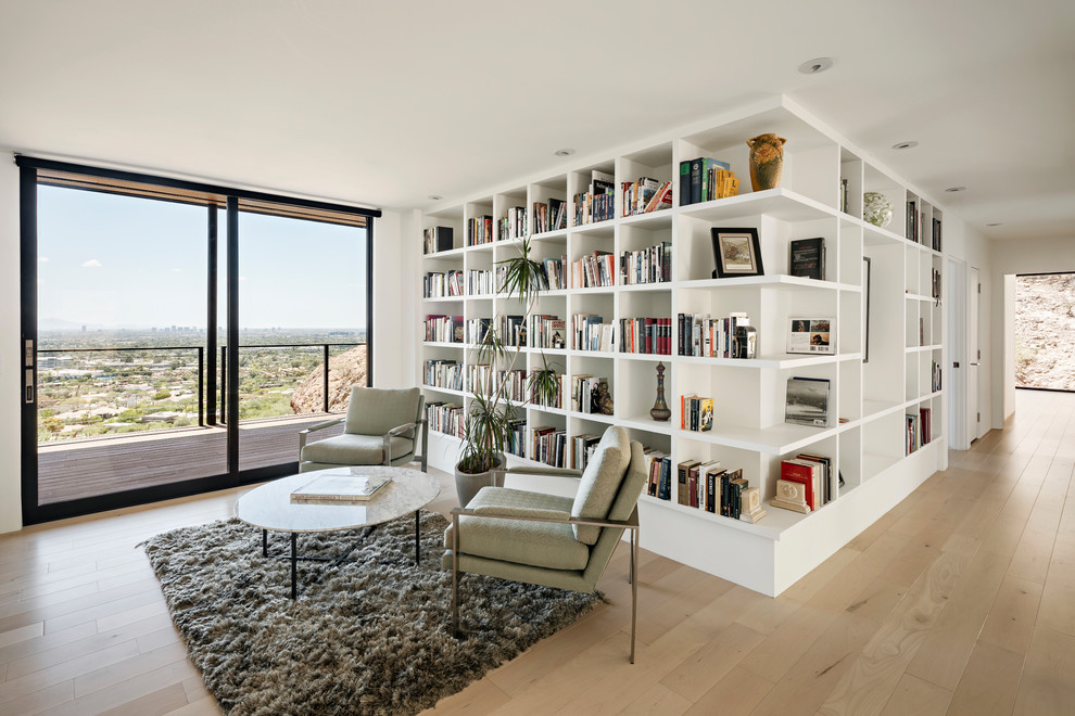 Foto di un soggiorno moderno con libreria, pareti bianche e parquet chiaro