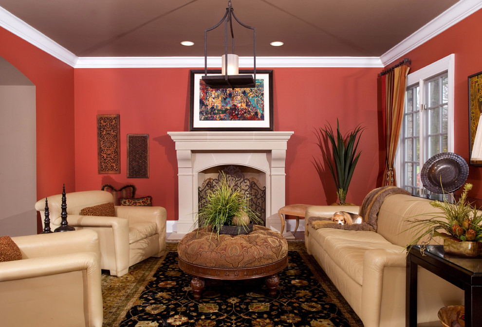 Cette photo montre un salon chic de taille moyenne et fermé avec un mur rouge, parquet foncé, une cheminée standard, un manteau de cheminée en plâtre et aucun téléviseur.