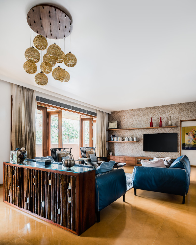 Источник вдохновения для домашнего уюта: парадная, открытая гостиная комната в средиземноморском стиле с белыми стенами, телевизором на стене, бежевым полом, синим диваном и обоями за телевизором