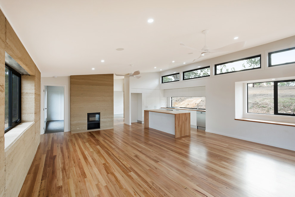 Photo of a medium sized contemporary open plan living room in Other with light hardwood flooring, a wood burning stove, a metal fireplace surround, a wall mounted tv and multi-coloured floors.