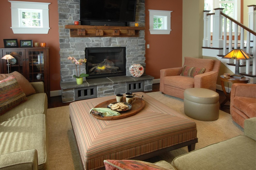 シアトルにある中くらいなトラディショナルスタイルのおしゃれなリビング (オレンジの壁、濃色無垢フローリング、標準型暖炉、石材の暖炉まわり、壁掛け型テレビ) の写真