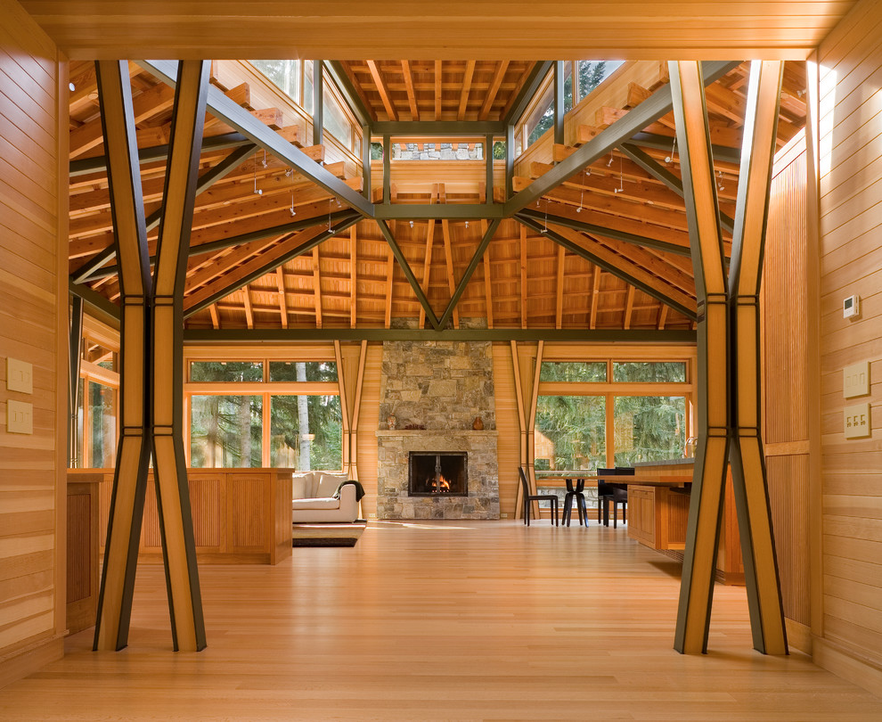 Diseño de salón abierto minimalista grande con suelo de madera en tonos medios, todas las chimeneas y marco de chimenea de piedra