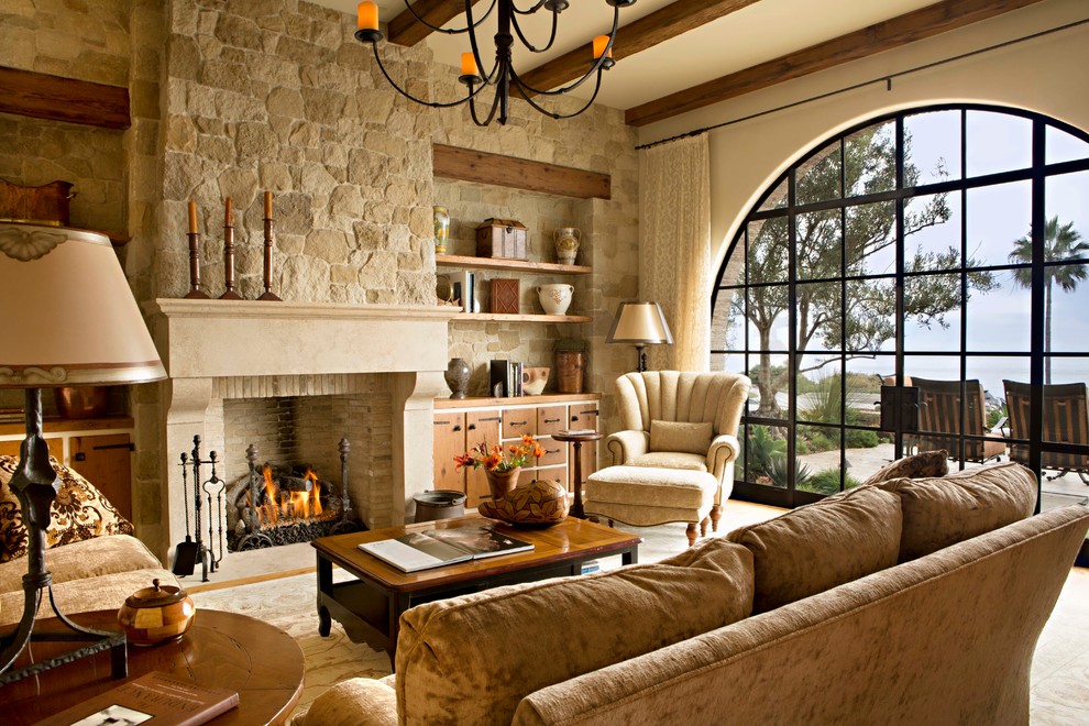 На фото: гостиная комната в средиземноморском стиле с бежевыми стенами, стандартным камином и фасадом камина из камня с