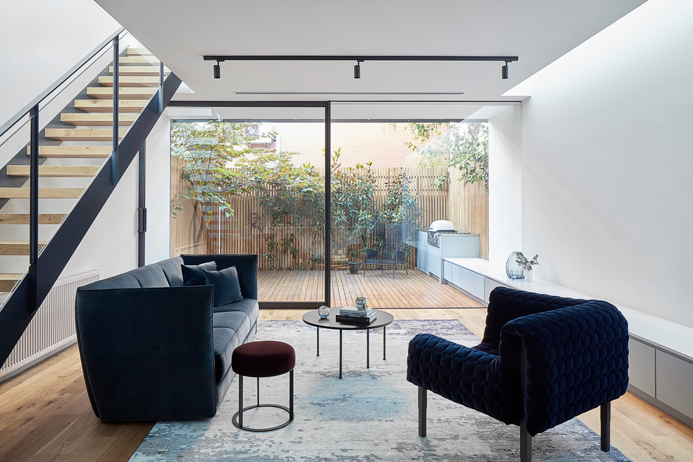 Modern formal mezzanine living room in Melbourne with white walls, light hardwood flooring and beige floors.